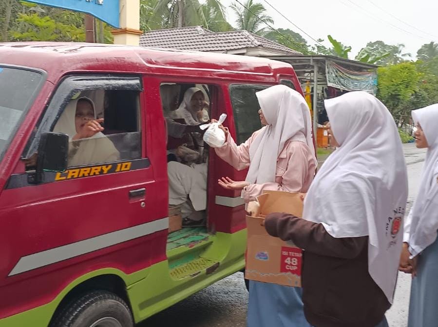 Beberapa siswa SMAN 1 Lampihong tergabung dalam organisasi OSIS, terlihat berdiri di pinggir jalan sembari membagikan bungkus makanan kepada penguna jalan yang melintas, dengan sasaran para jamaah majelis Guru Bakhiet. ( Foto: rin/LK).