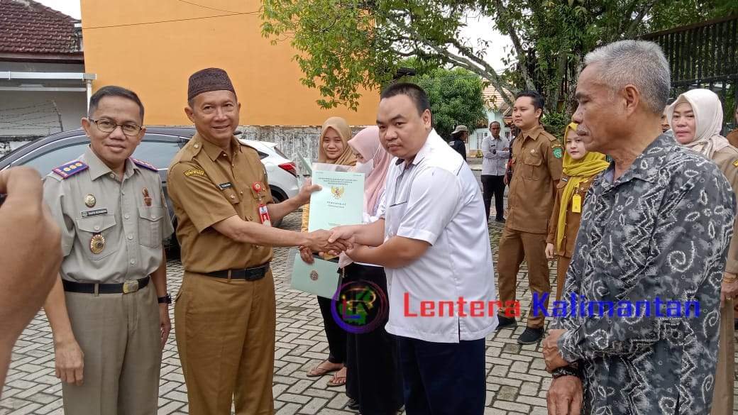 Kepala Dinas Perindustrian Tapin Yustan Azidin dan Kepala Badan Pertanahan Negara (BPN) Tapin Taufik Rokhman saat menyerahkan Sertifikat SHAT di halaman Kantor Dinas Perindustrian, Senin (5/2/ 2024). Foto: Ay/lenterakalimantan.com