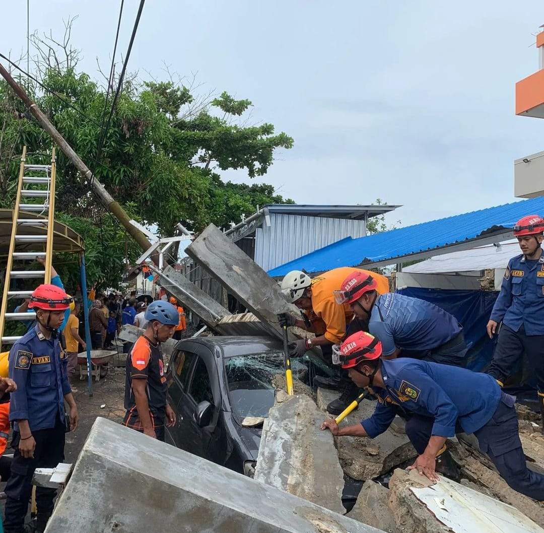 Rekanan Damkar Kota Banjarmasin sedang membantu pihak BPBD mengevakuasi satu unit mobil yang tertimpa bangunan pagar beton, Kamis (8/2/2024). Foto: BPBD Kota Banjarmasin.