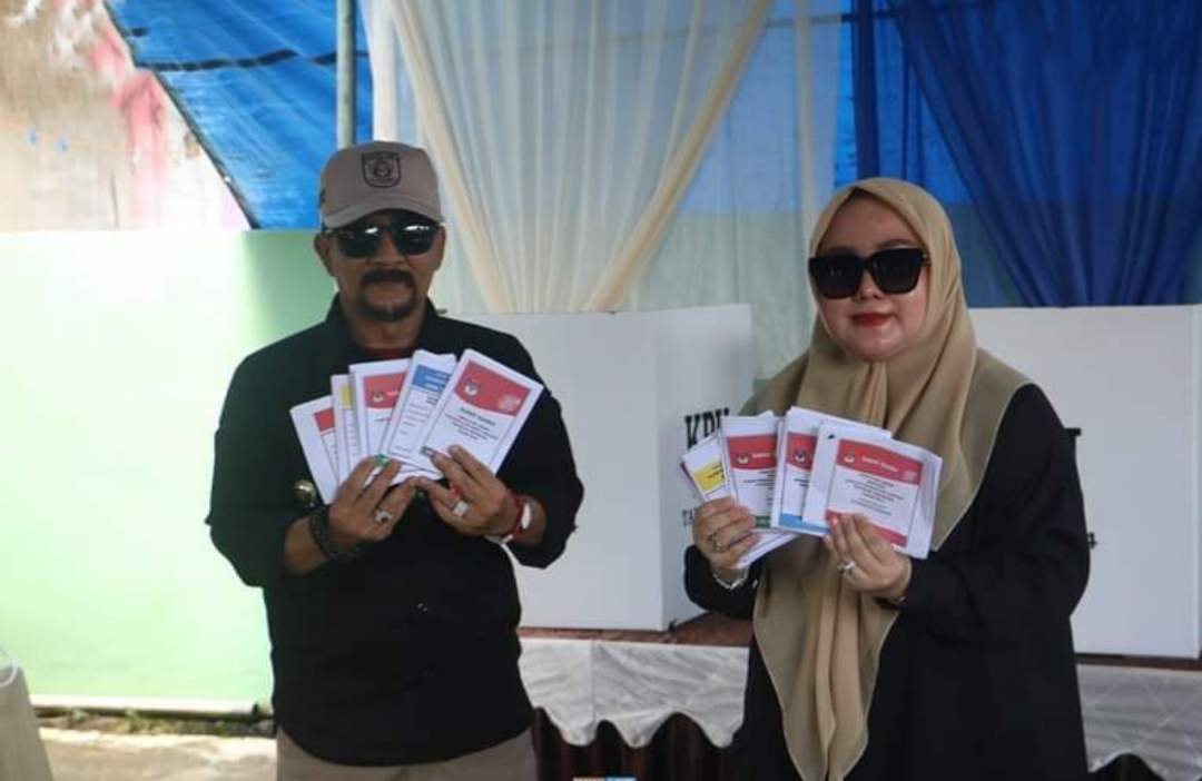 Pj Bupati Syamsir bersama Istri memberikan suaranya di TPS 011 Kelurahan Pelaihari. Foto; Diskominfo/Tala