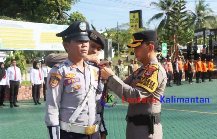Kapolres Balangan AKBP Riza Muttaqin saat melakukan penyematan pita kepada salah seorang anggota di jajaran Dinas Perhubungan setempat, pada apel gelar pasukan Operasi Terpusat Ketupat Intan 2024. Foto: Windi/lenterakalimantan.com