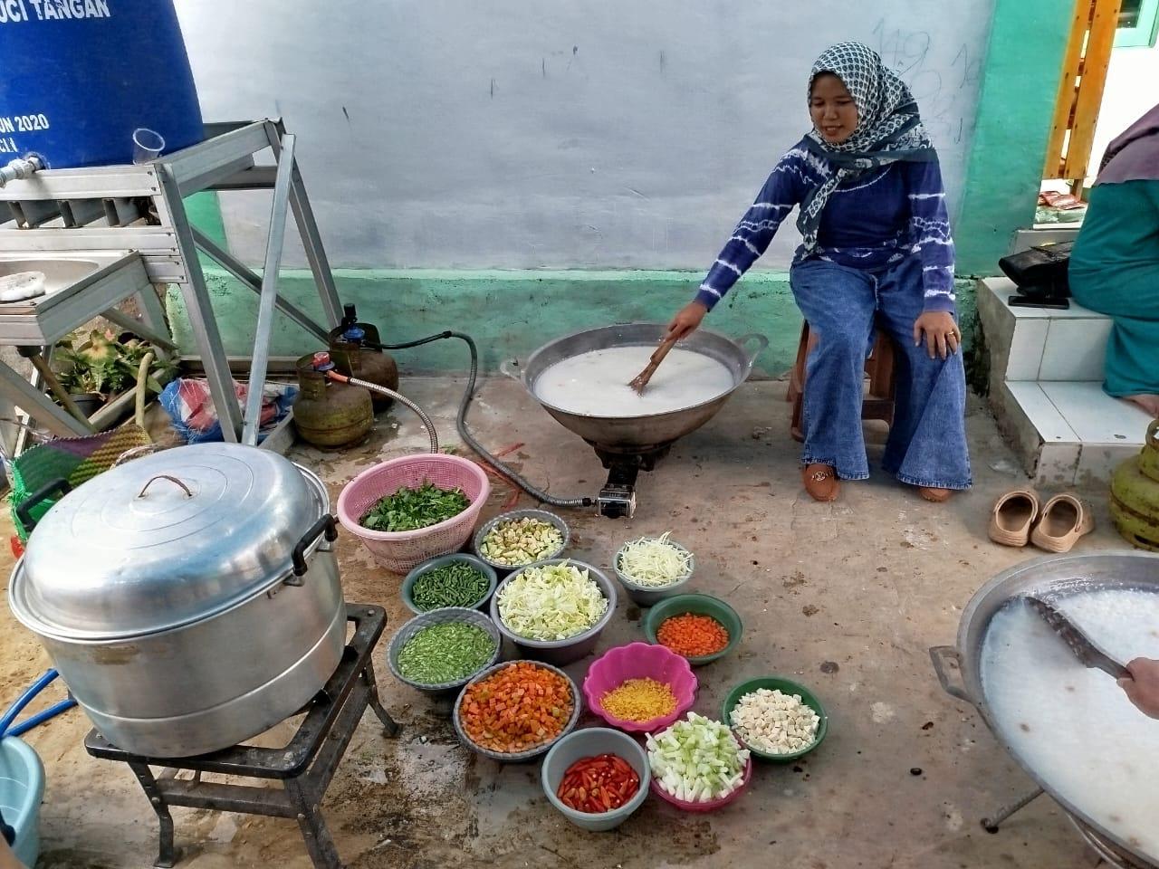 Salah satu warga Rt. 004 sedang asyik mengaduk bubur asyura. Foto: Arif/lenterakalimantan.com
