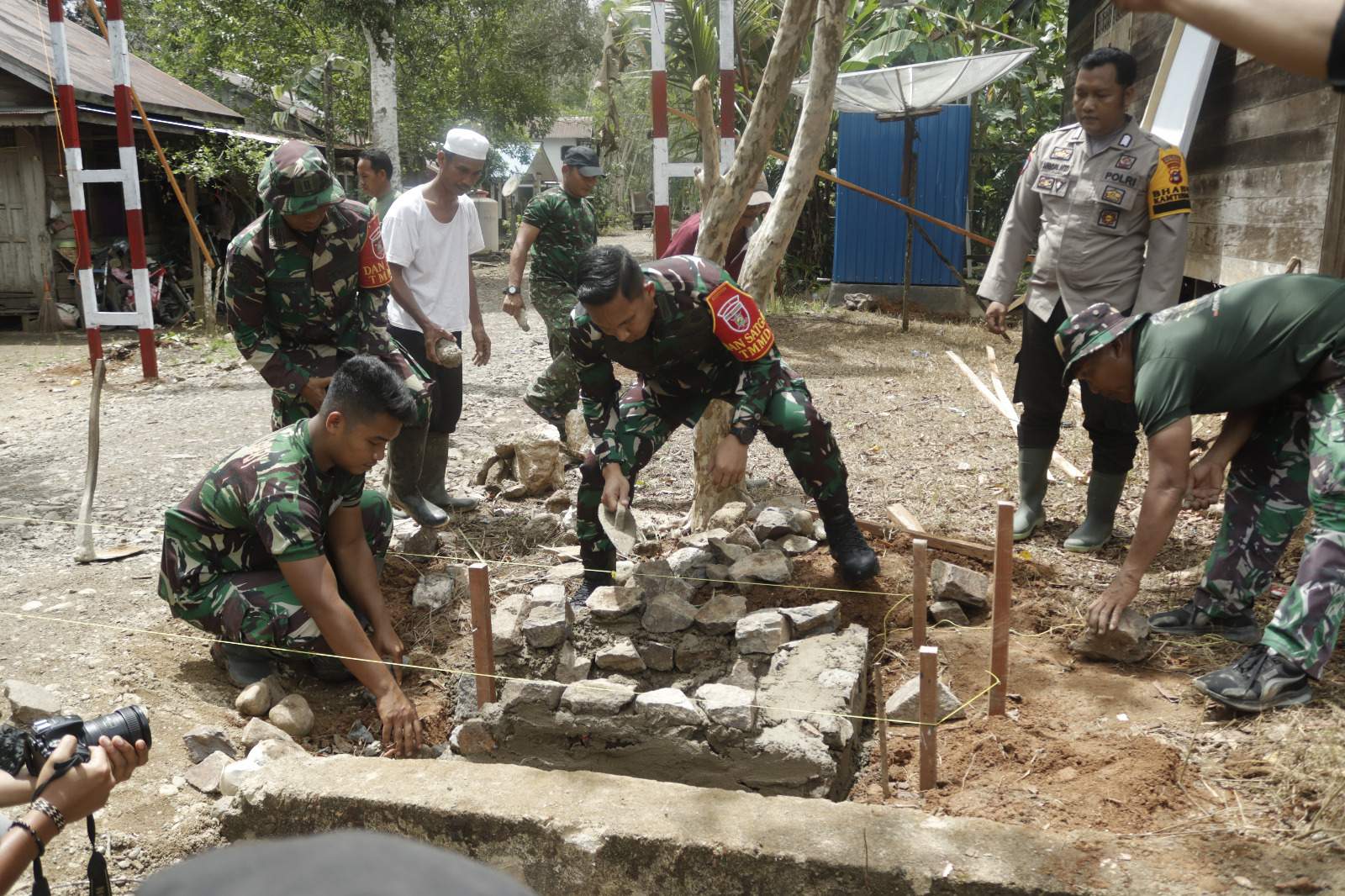 Dan Satgas TMMD ke 121 Letkol Inf Bayu Oktavianto Sudibyo saat ikut turun tangan bergotong royong memulai pembuatan pondasi bakal gapura. Foto Pendim HSS