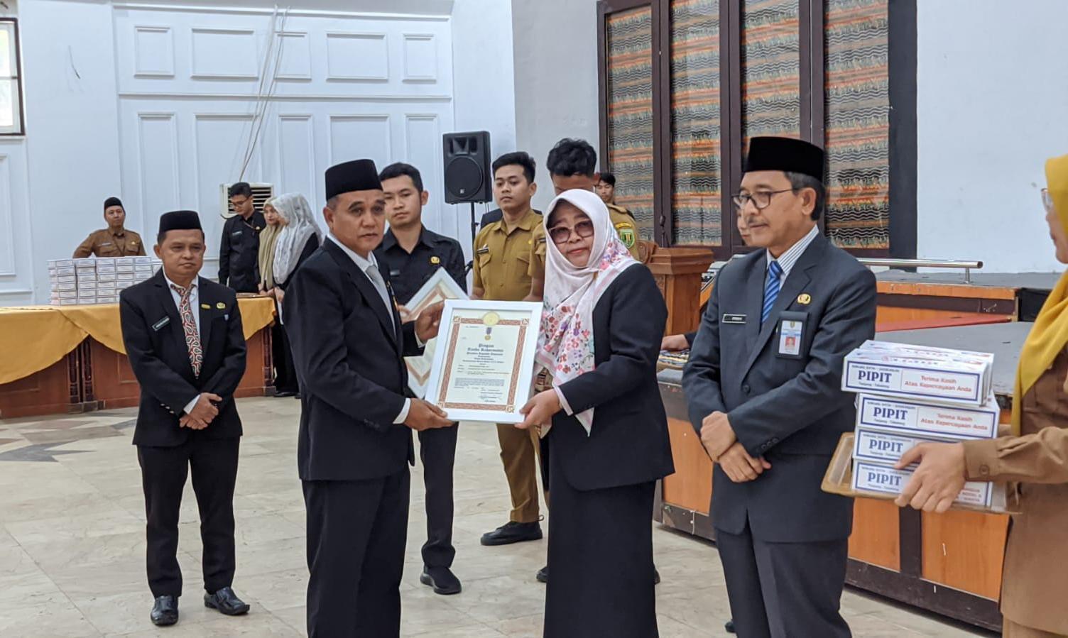 Pj Bupati Tabalong Hj Hamida Munawarah menyerahkan piagam SLKS. Foto: JM/lenterakalimantan.com