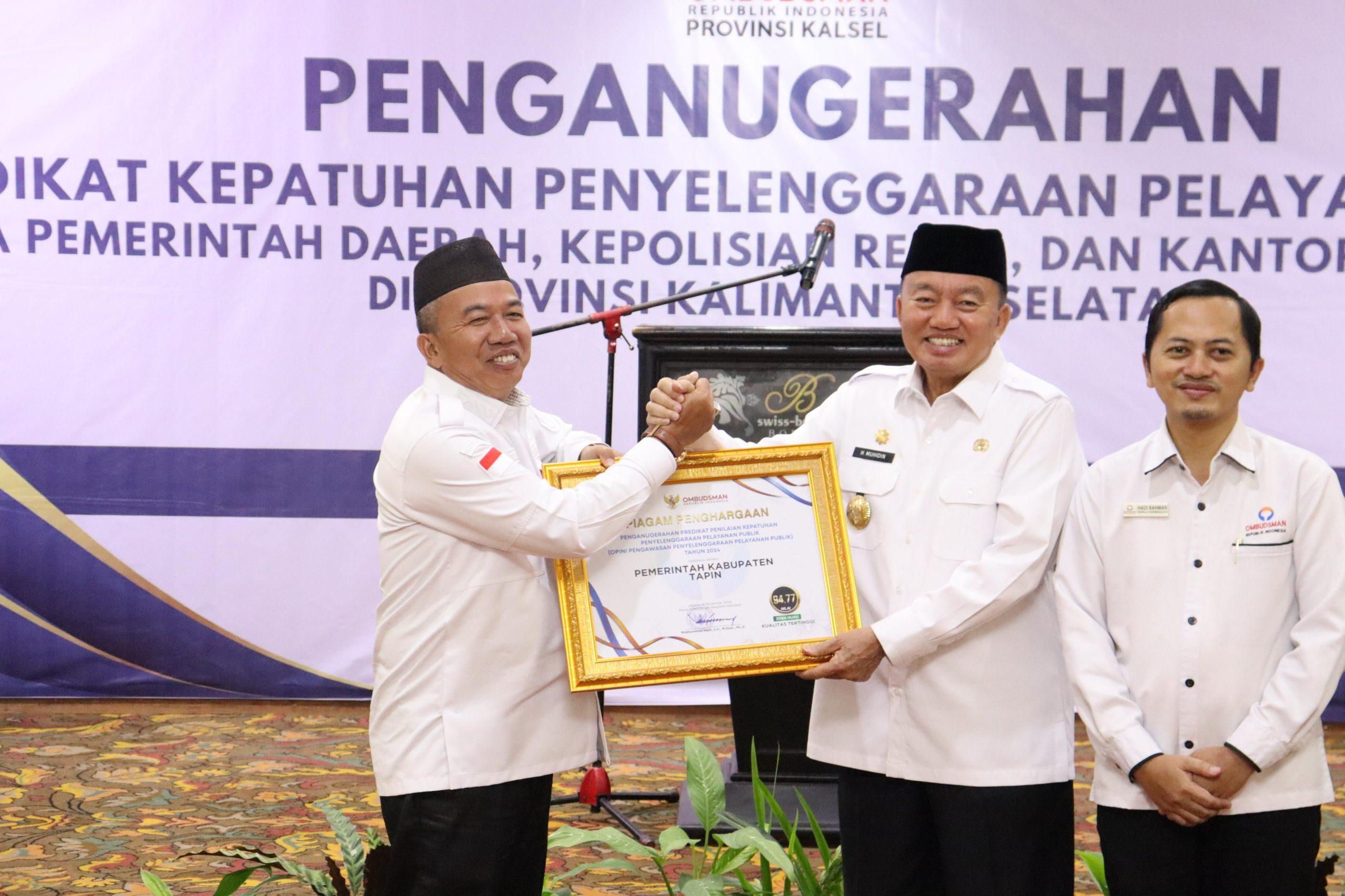 Pj Bupati Tapin M Syarifuddin saat menerima penghargaan atas Predikat Penilaian Kepatuhan Penyelenggaraan Pelayanan Publik dari Ombudsman RI yang diserahkan oleh PLT Gubernur Kalsel H Muhidin.