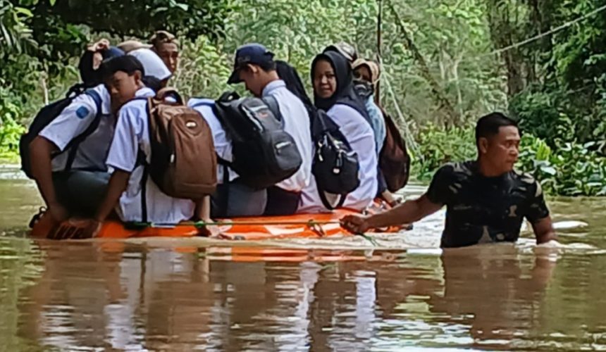Bantu sejumlah siswa untuk berangkat sekolah, anggota Koramil 1001-01 Juai, Kodim 1001 HSU-BLG, Sertu Ashadi, berjuang sekuat tenaga menarik perahu karet ditengah banjir yang melanda Desa Juai Kecamatan Juai, Balangan. Foto: Pendim 1001/HSU-BLG
