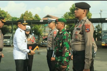 Bupati Rahmat secara simbolis memasang pita pada salah satu anggota di Apel Gelar Pasukan Operasi Ketupat Intan 2025. Foto: Asep/lenterakalimantan.com