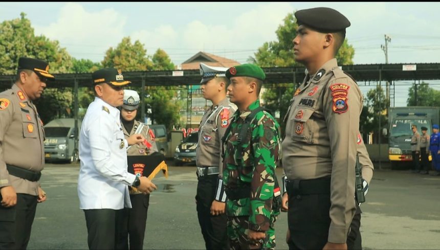 Bupati Rahmat secara simbolis memasang pita pada salah satu anggota di Apel Gelar Pasukan Operasi Ketupat Intan 2025. Foto: Asep/lenterakalimantan.com