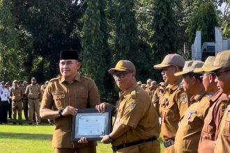 Teks foto// Bupati Rahmat menyerahkan penghargaan pada Apel bersama ( dok foto Asep)