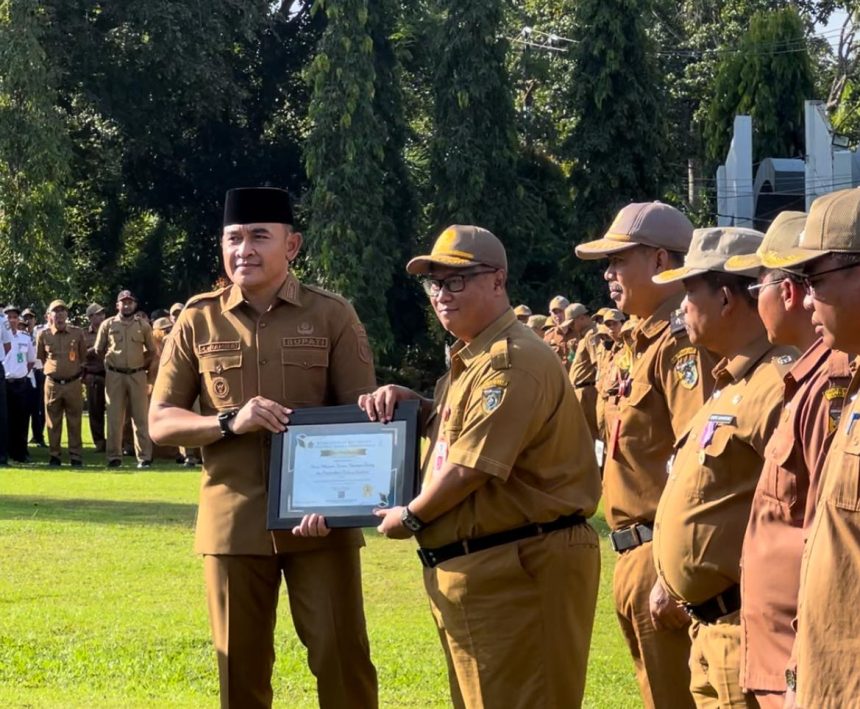 Teks foto// Bupati Rahmat menyerahkan penghargaan pada Apel bersama ( dok foto Asep)