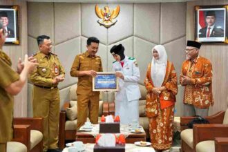 Bupati Banjar H Saidi Mansyur menyerahkan penghargaan berupa paket umrah kepada Siti Nur Adlina yang berhasil menjadi anggota Paskibraka Tingkat Nasional 2026, di Mahligai Sultan Adam Martapura, Senin (24/8/26).